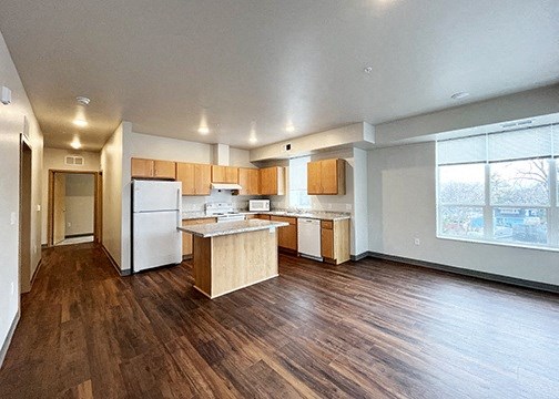 a large kitchen with wooden floors and white appliances
