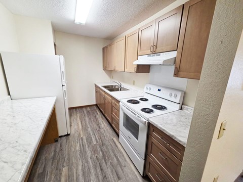 A kitchen with a white fridge, white stove, and brown cabinets.