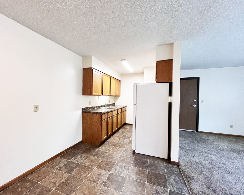 A kitchen with white appliances and wooden cabinets.