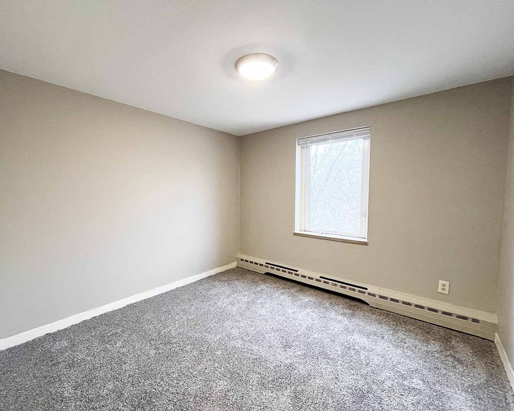 A room with a window and carpeted floor.