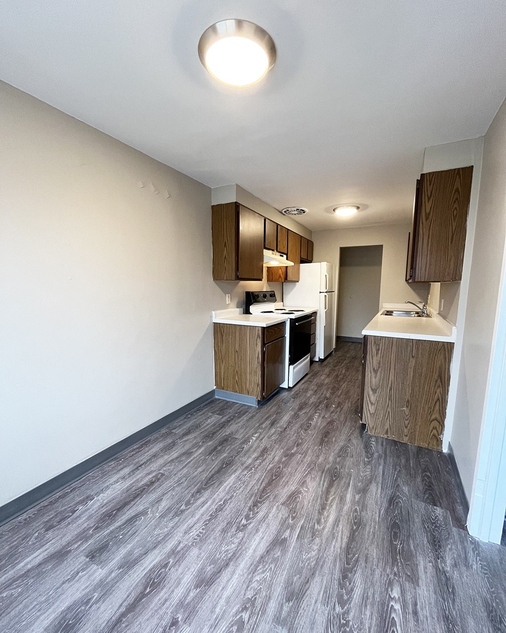 A kitchen with wooden cabinets and a grey floor.