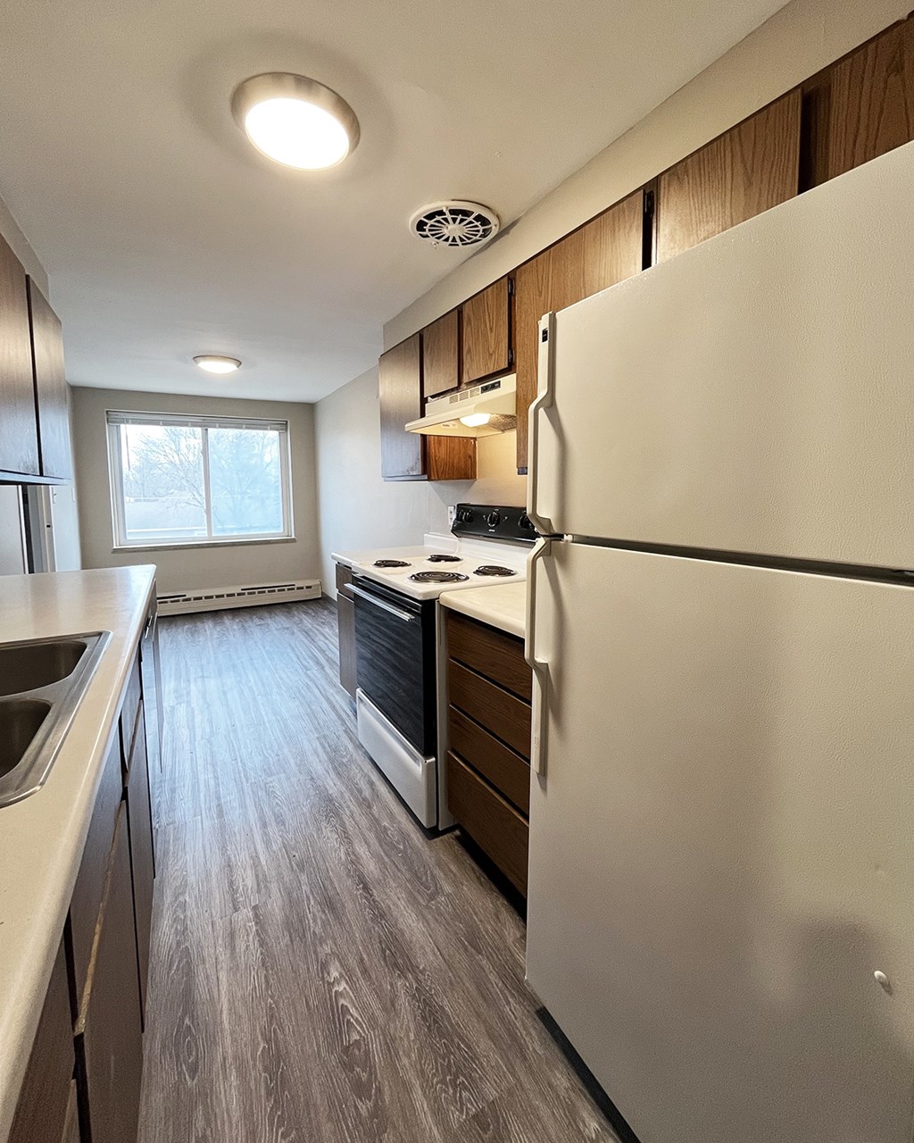 A kitchen with a white refrigerator, sink, and stove.