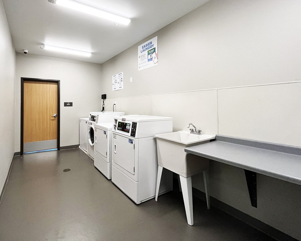 A laundry room with washers and dryers and a sink.