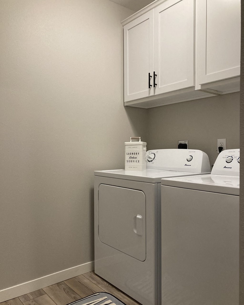 a washer and dryer in a laundry room with white cabinets