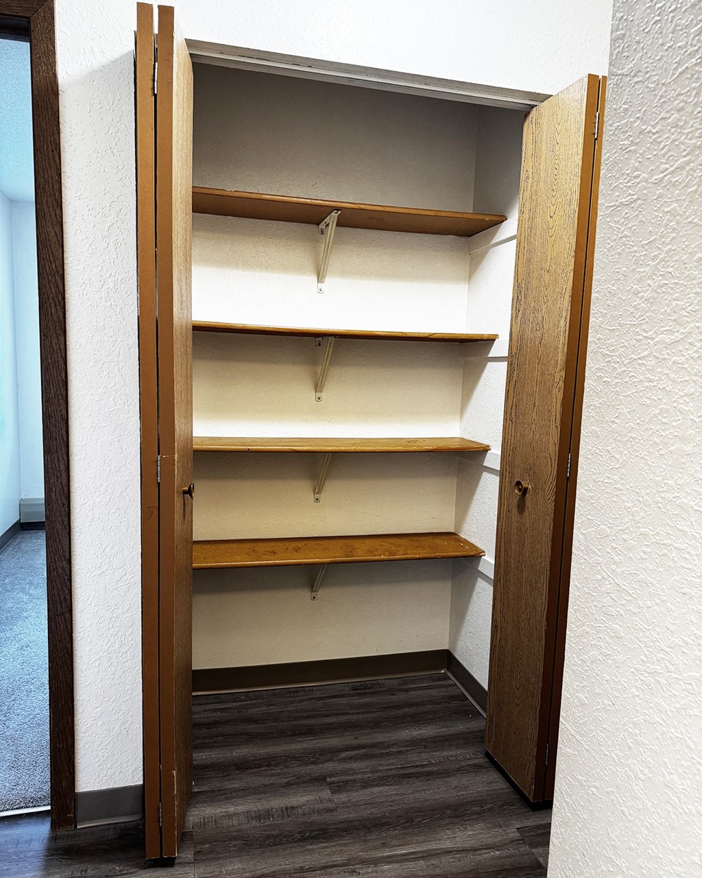 A white wall with a brown shelf and a brown door.