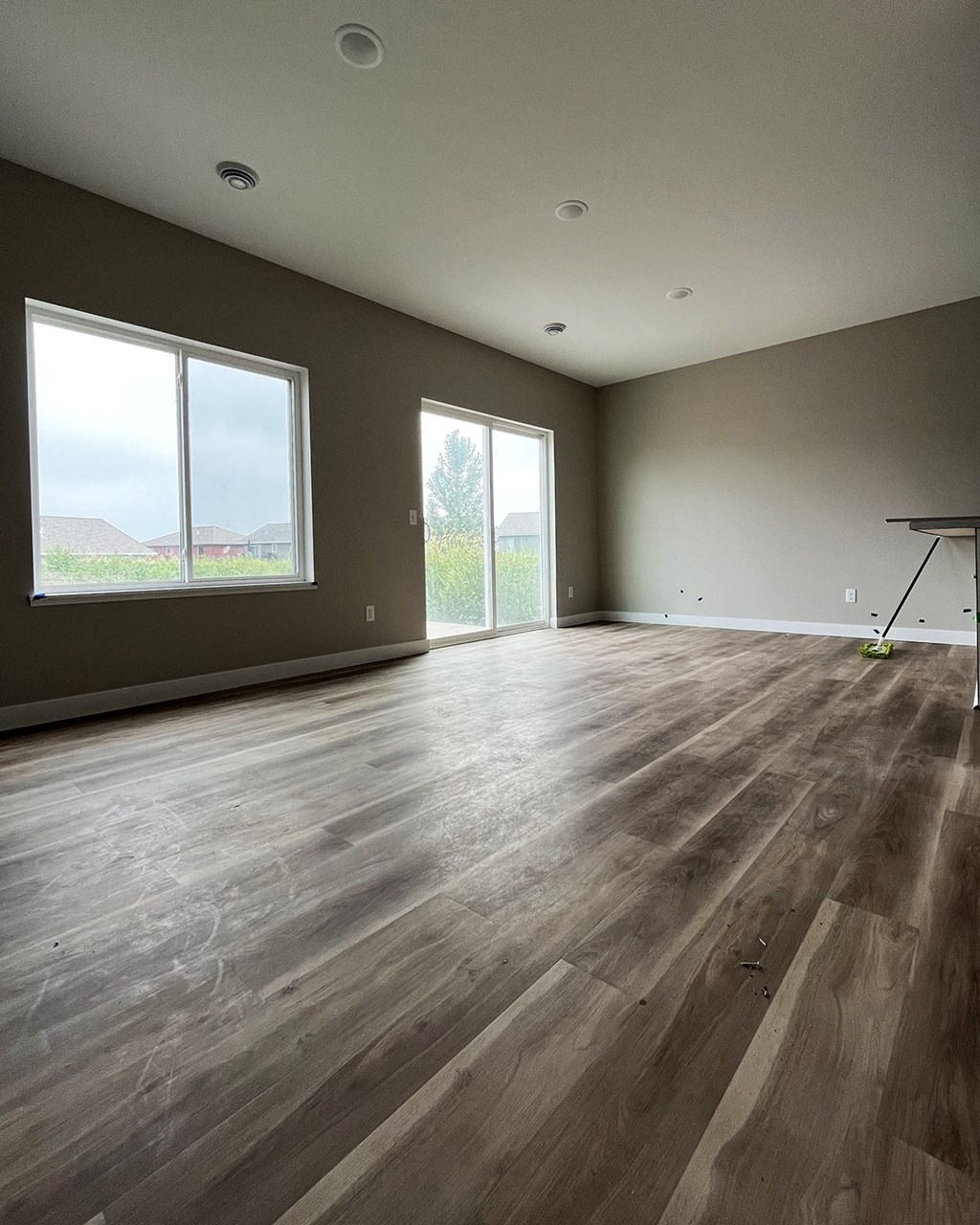 an empty living room with a large window and a table with a tennis racquet