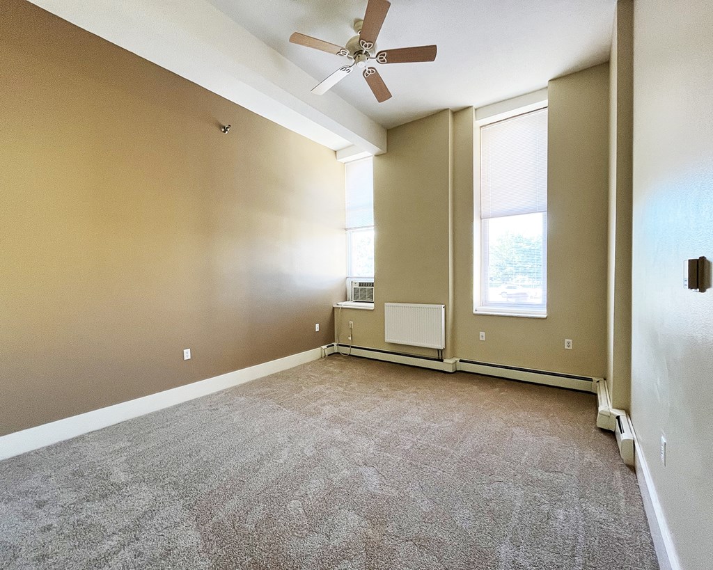 A room with a ceiling fan and carpeted floor.