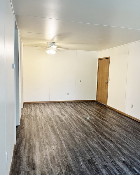 an empty living room with wood flooring and white walls