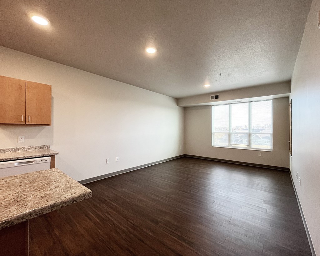 A spacious room with wooden floors and a granite countertop.