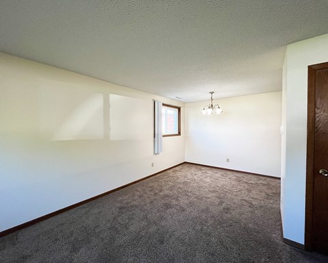 an empty living room with white walls and carpet