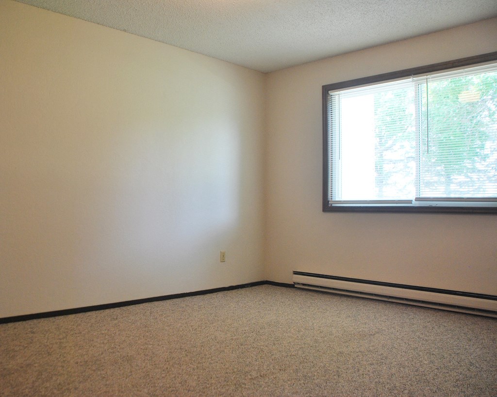 a bedroom with a large window and a carpeted floor