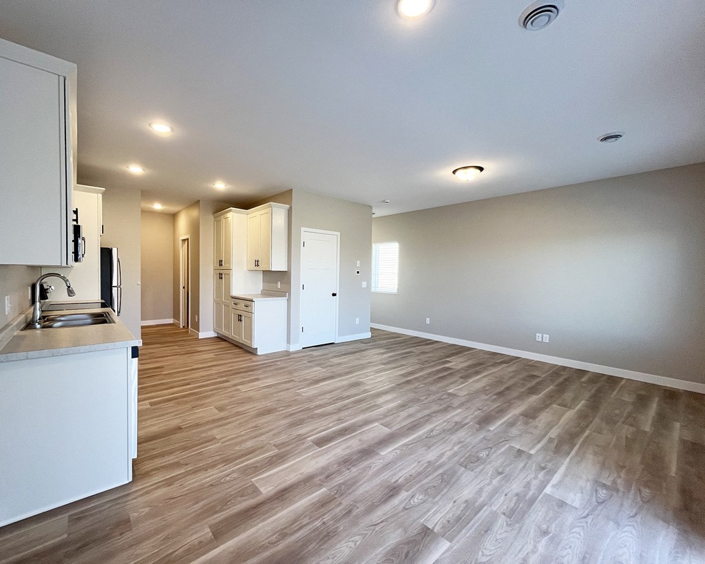 an empty living room and kitchen with a wood floor