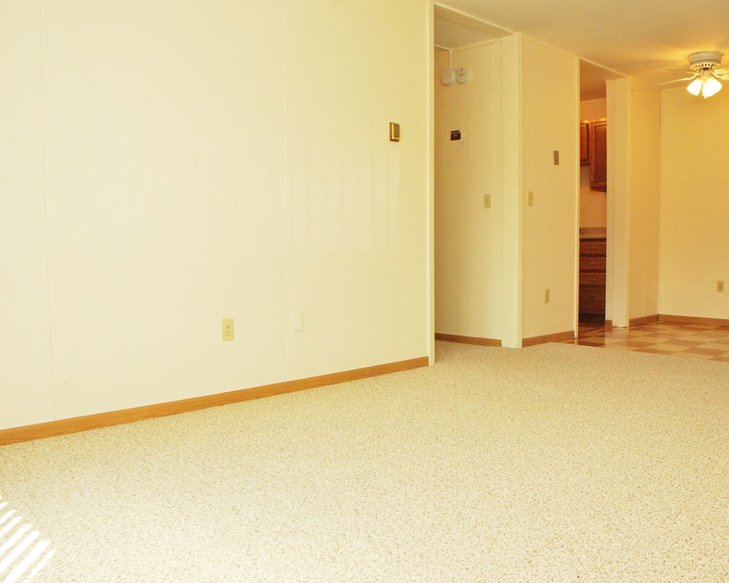an empty living room with the door open to a hallway
