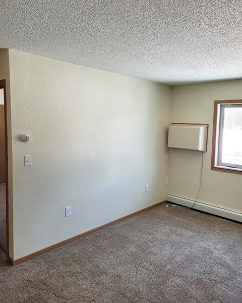 an empty living room with a heater and a window