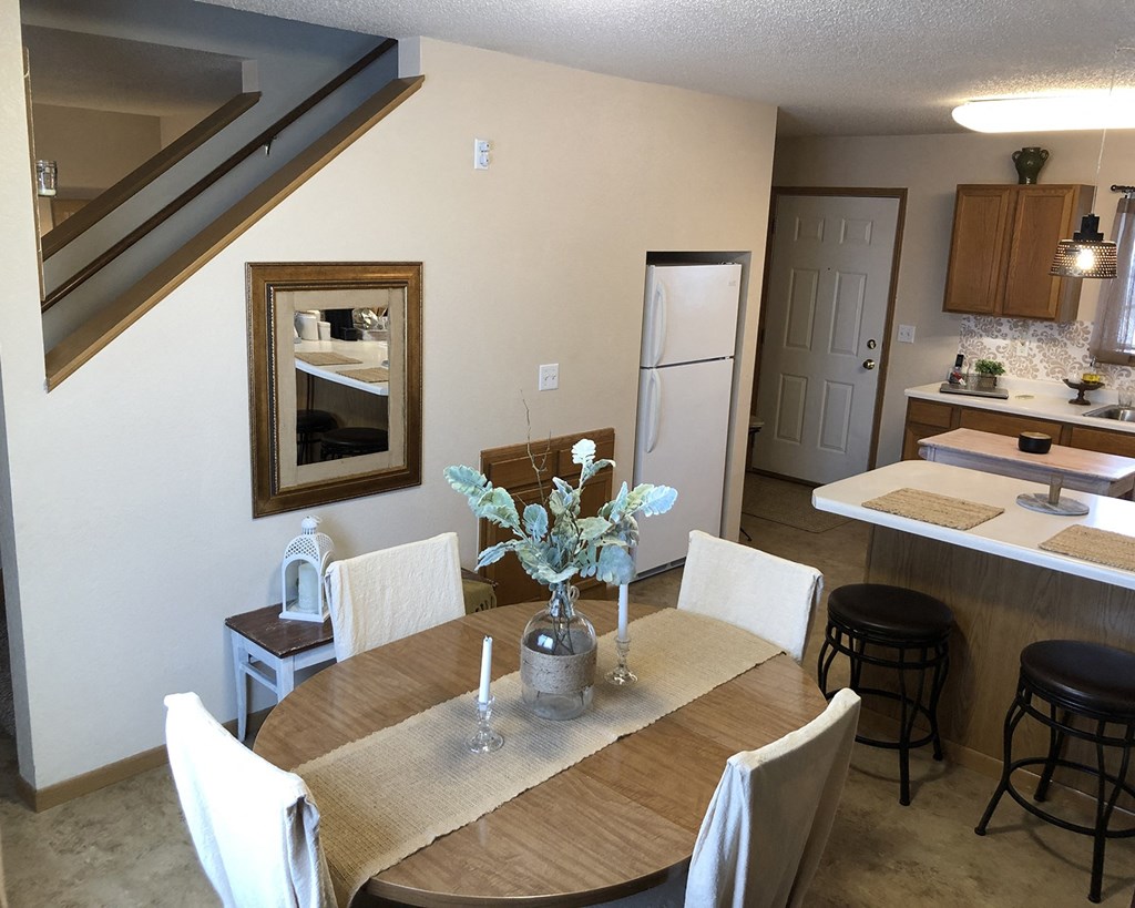 a dining area with a table and chairs and a kitchen in the background