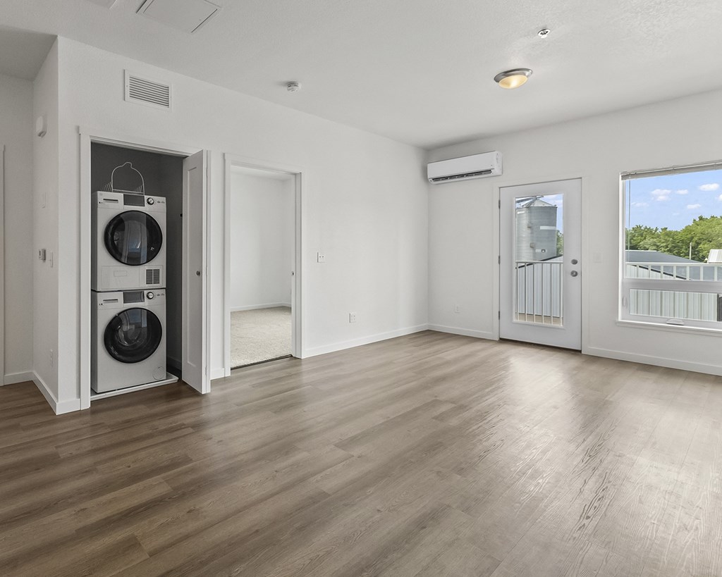 the living room of an apartment with a washer and dryer on the wall