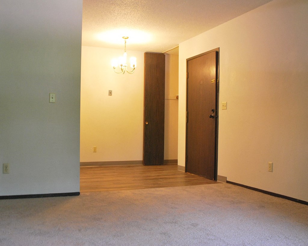 a empty living room with a wood floor and a door to a closet