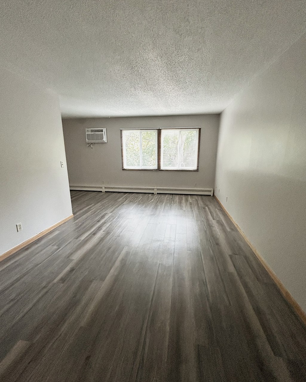 an empty living room with wood floors and a window