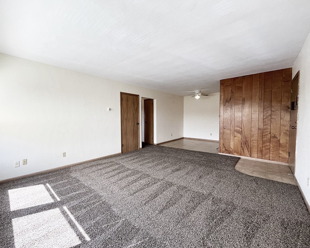 an empty living room with carpet and white walls