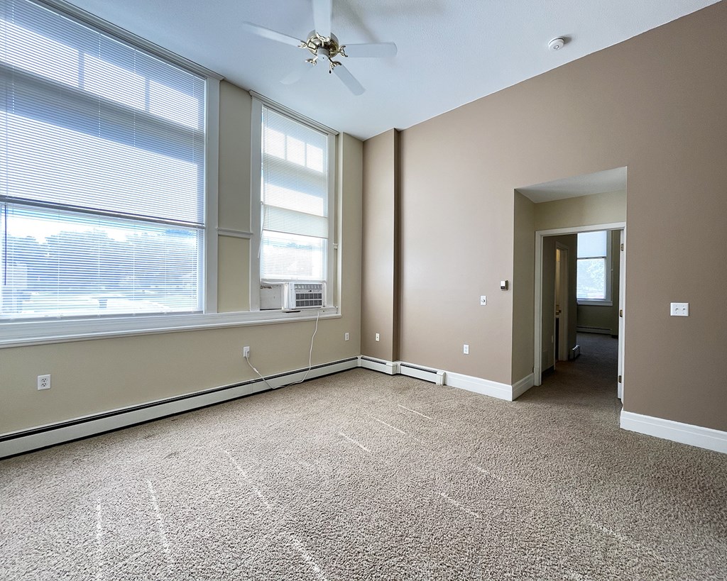 A room with a carpet floor and a ceiling fan.
