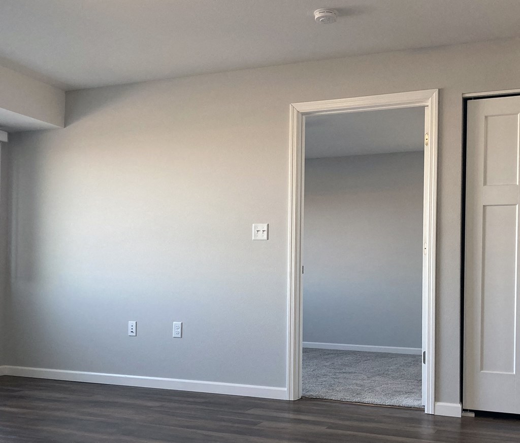 an empty living room with a door open to a hallway