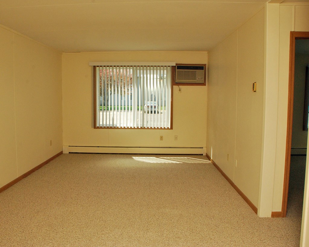 an empty room with a window and a air conditioner