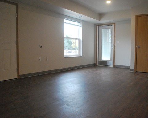 an empty living room with wood floors and a window