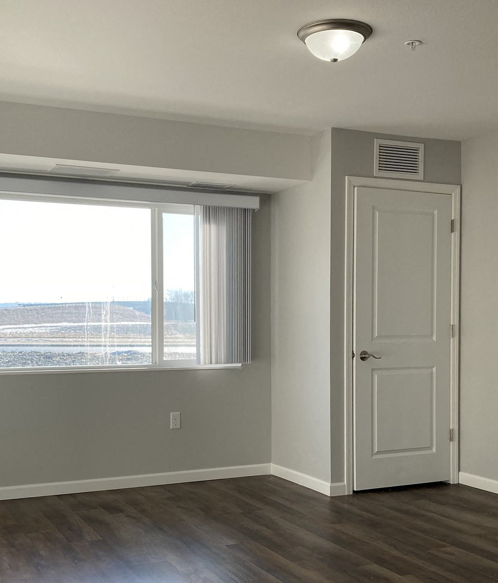 an empty living room with a window and a door