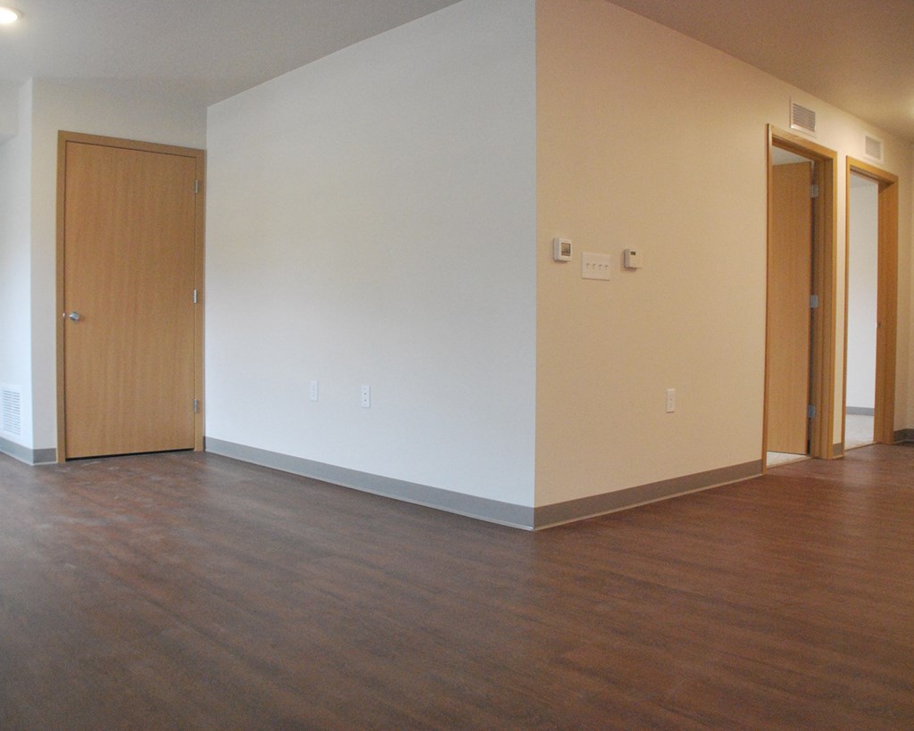 an empty living room with wood floors and white walls