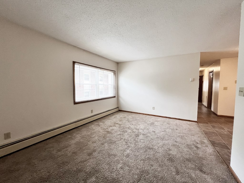 A room with a carpeted floor and a window letting in light.