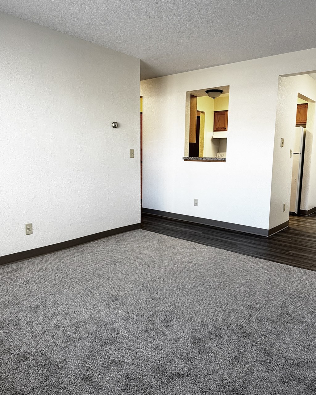 A room with a grey carpet and a mirror on the wall.