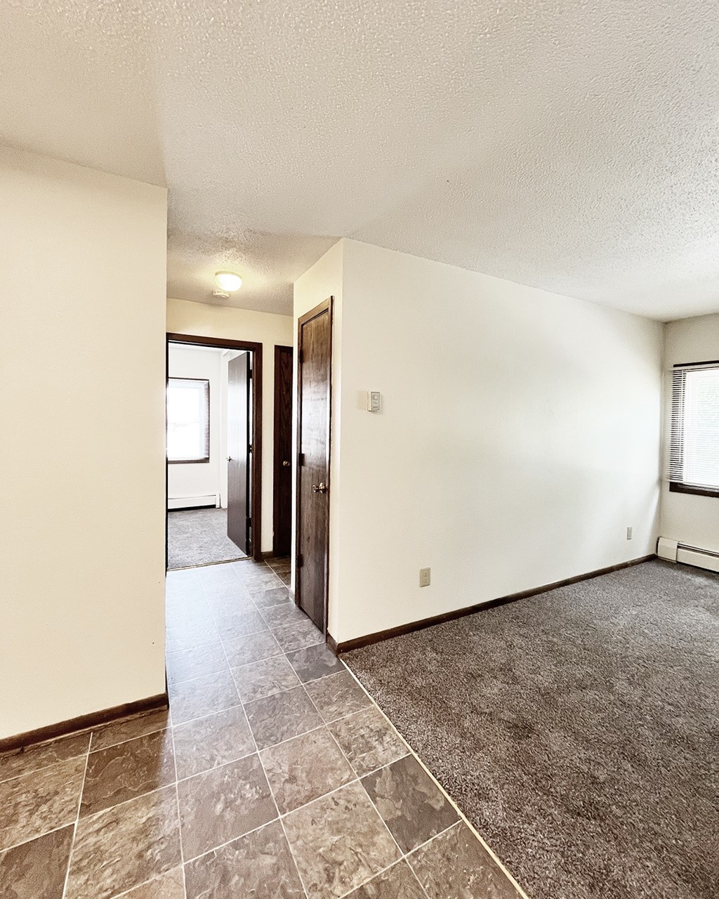 A room with a tile floor and a door leading to another room.