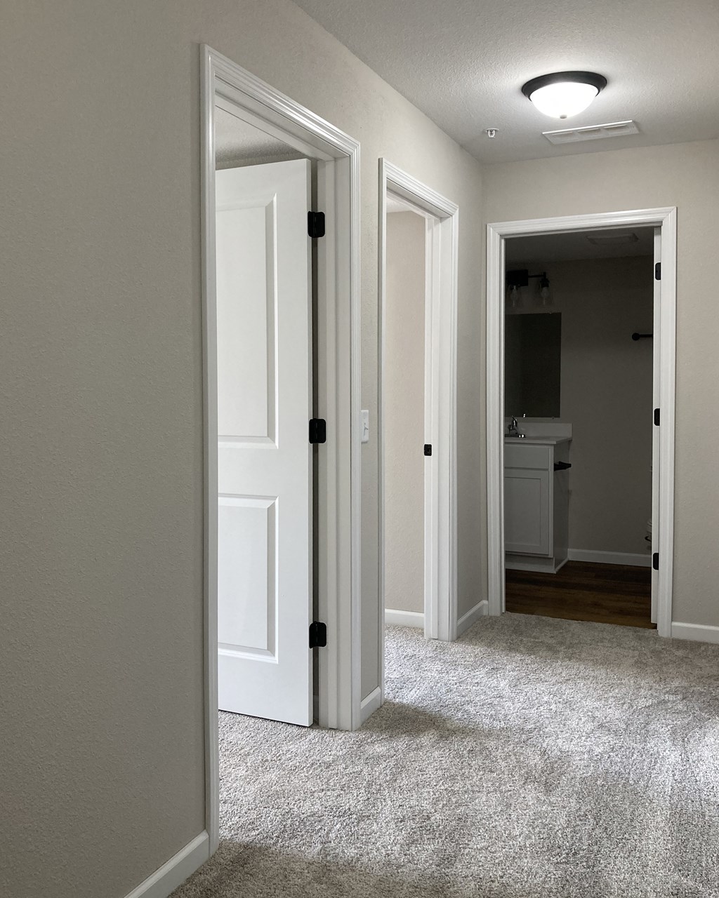 a doorway into a bedroom with a carpeted floor and a bathroom in the background
