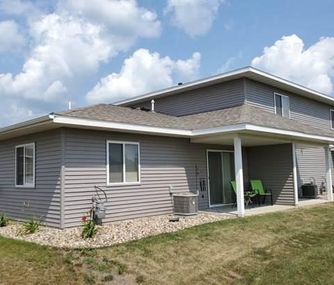 A house with a grey siding and a green chair on the porch.