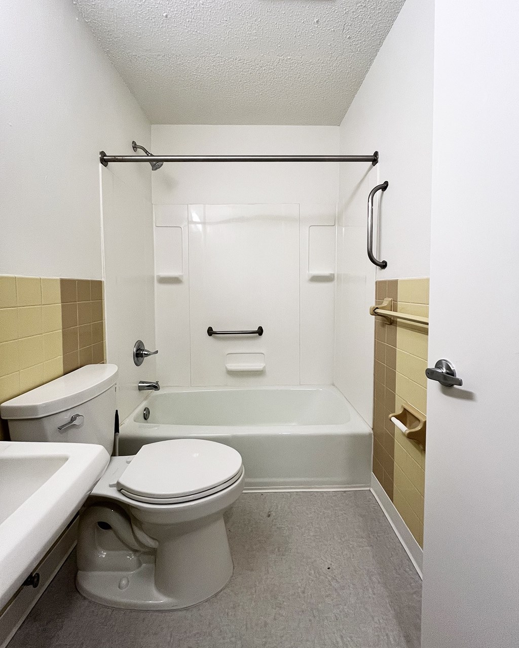 A white toilet sits in a bathroom next to a bathtub.