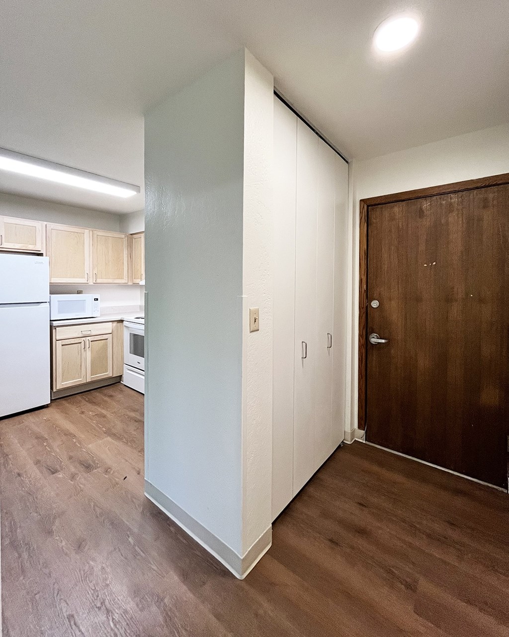 A kitchen with white cabinets and a white fridge.