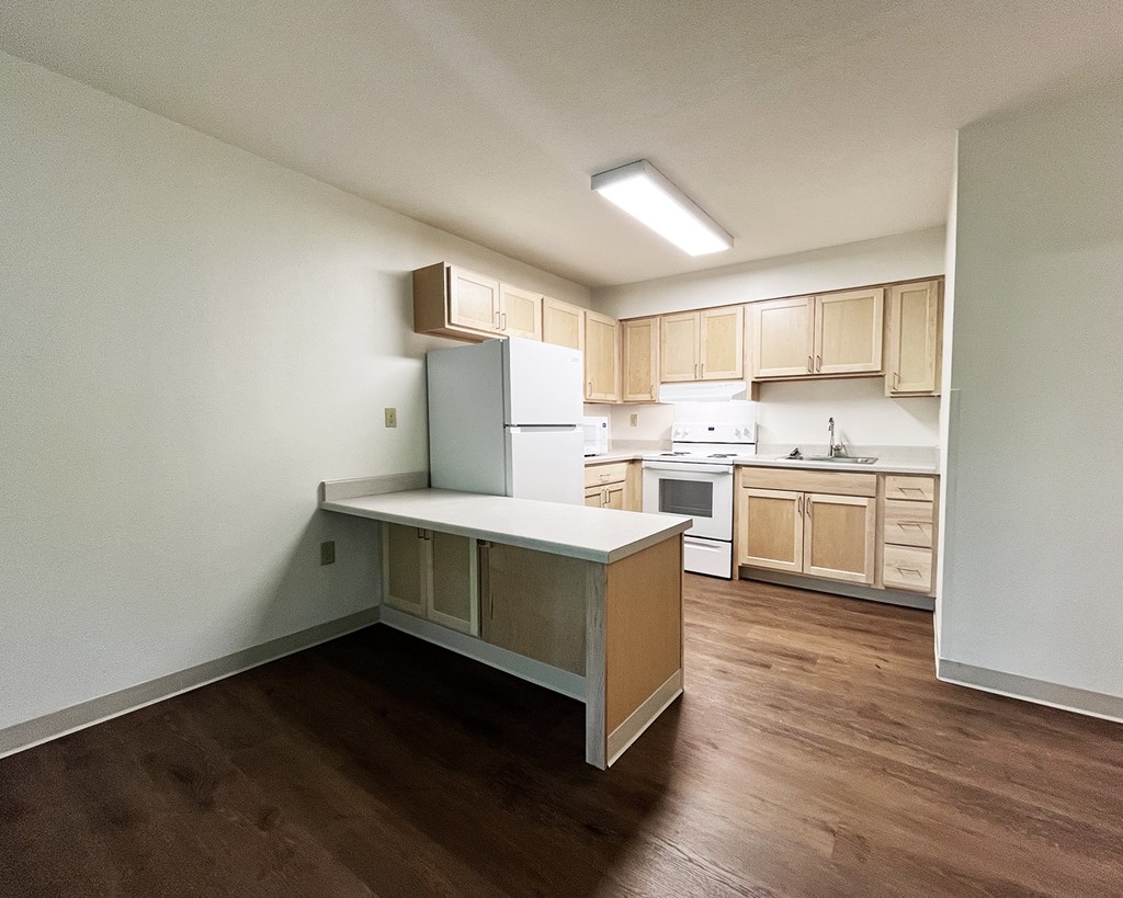 A kitchen with wooden floors and white walls.