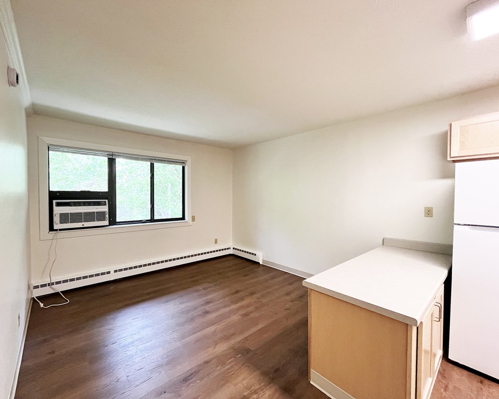 A room with a window and a white fridge.