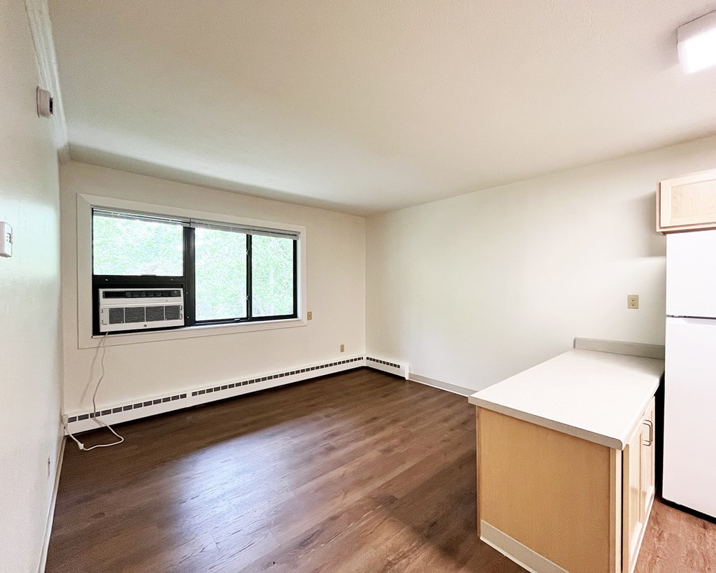 A room with a window and a white fridge.
