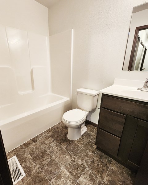 A white toilet sits in a bathroom next to a bathtub.