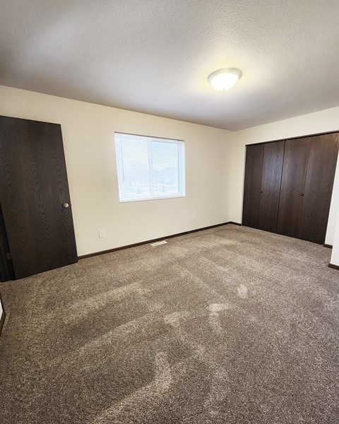 A room with a carpeted floor and a window.