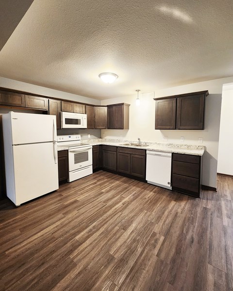 A kitchen with white appliances and brown cabinets.
