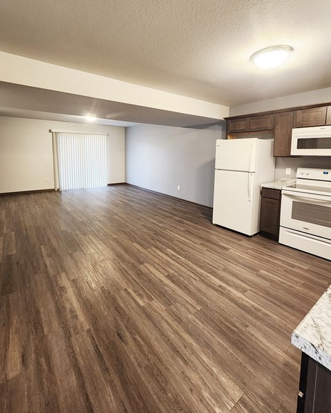 A kitchen with a white refrigerator and wooden flooring.