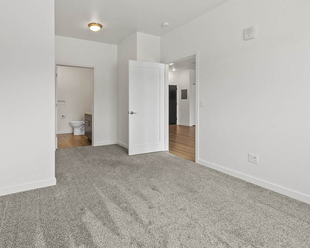 a living room with a carpeted floor and a door to a bathroom