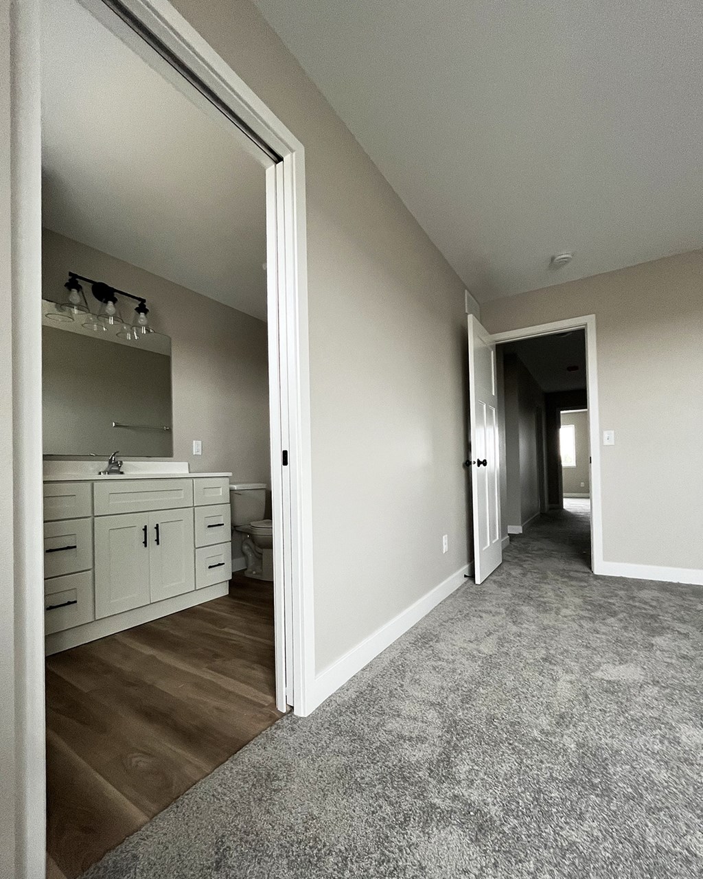 a bedroom with a large mirror and a bathroom with a sink and toilet