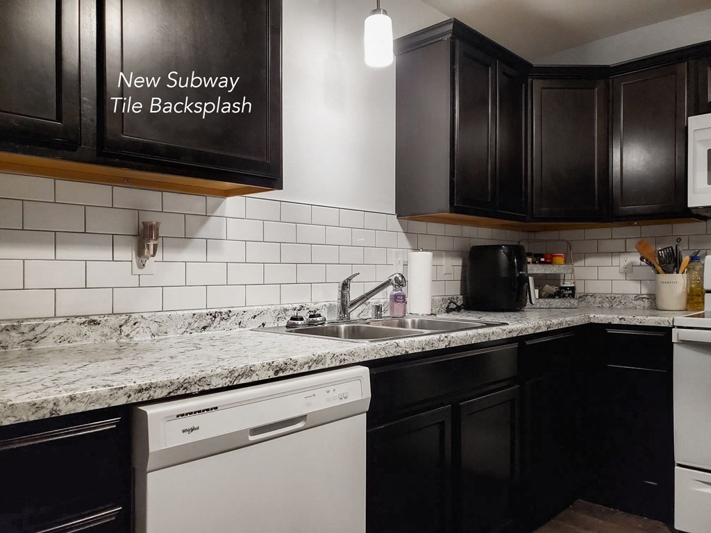 a white and black kitchen with black cabinets and marble counter tops