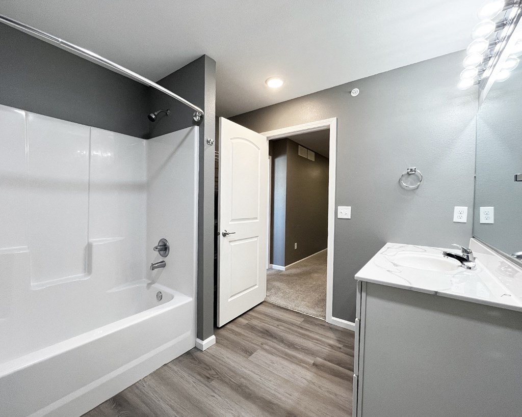 A bathroom with a white tub and sink, and a white door.