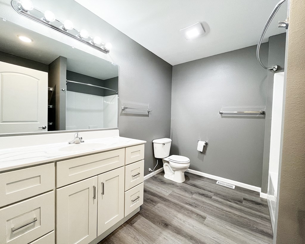 A bathroom with a white counter top and a white toilet.
