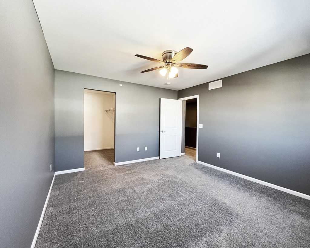 A room with a ceiling fan and carpeted floor.