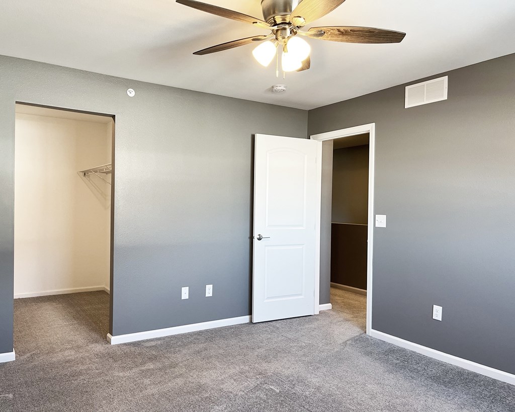 A room with a ceiling fan and carpeted floor.